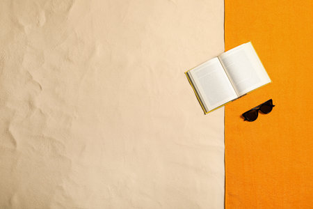 Beach towel, book and sunglasses on sand, flat lay. Space for textの写真素材