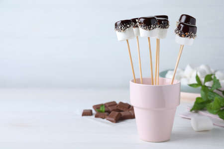 Delicious marshmallows covered with chocolate on white wooden table. Space for textの写真素材