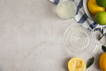 Glass squeezer with juice and lemons on light table, flat lay. Space for textの写真素材