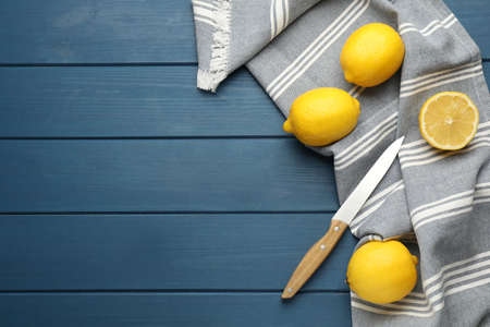 Striped kitchen towel, lemons and knife on blue wooden table, flat lay. Space for textの写真素材