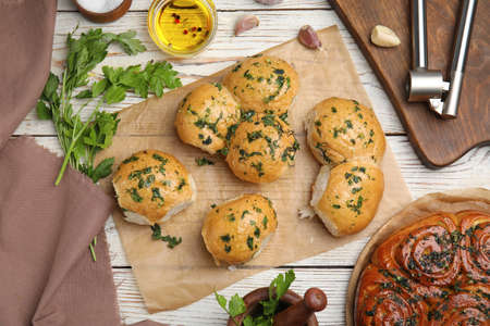 Traditional Ukrainian bread (Pampushky) with garlic on white wooden table, flat lay