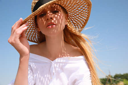 Beautiful woman with straw hat against blue sky on sunny dayの写真素材