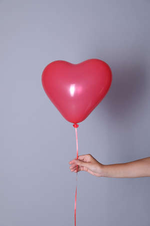 Woman holding heart shaped balloon on light background, closeupの写真素材