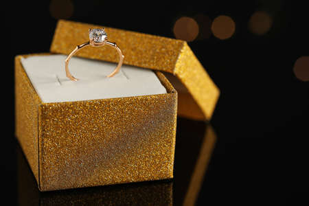 Beautiful engagement ring in box against blurred festive lights, space for textの写真素材