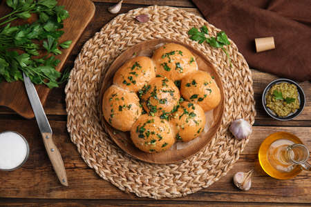 Traditional pampushka buns with garlic and herbs on wooden table, flat layの写真素材