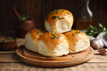 Traditional pampushka buns with garlic and herbs on wooden tableの写真素材