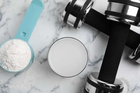 Amino acid shake, powder and dumbbells on white marble table, flat lay