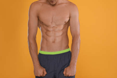 Shirtless man with slim body on yellow background, closeupの写真素材