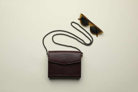 Stylish woman's bag and sunglasses on light background, flat layの写真素材