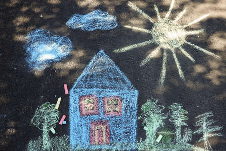 Child's house drawing and pieces of color chalk on asphalt, flat layの写真素材