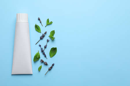 Blank tube of toothpaste with mint and lavender flowers on turquoise background, flat lay. Space for textの写真素材