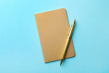 Stylish kraft planner with pen on light blue background, top viewの写真素材