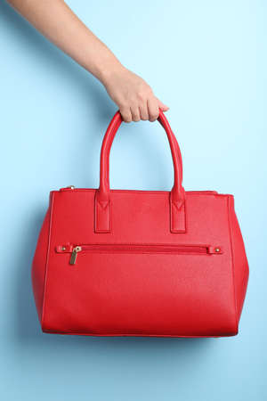 Woman holding stylish bag on light blue background, closeupの写真素材