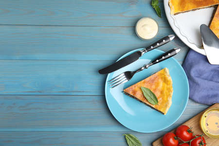 Piece of delicious pie with minced meat and basil served on light blue wooden table, flat lay. Space...