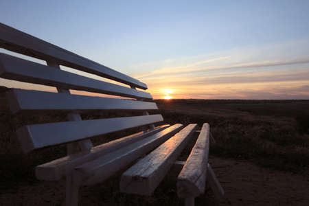 Wooden bench in field at sunrise, closeup. Early morning landscapeの写真素材