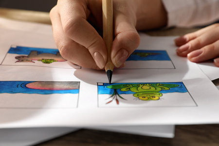 Woman drawing cartoon sketch in storyboard at workplace, closeup. Pre-production processの写真素材