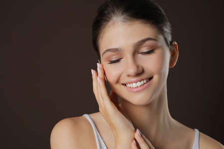 Portrait of pretty girl on brown background. Beautiful face with perfect smooth skinの写真素材