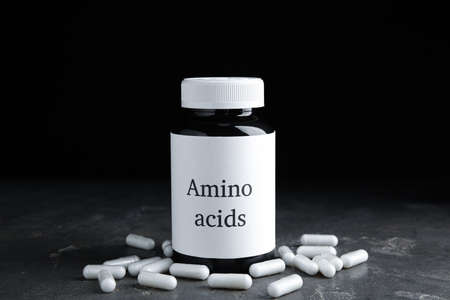 Amino acid pills and jar on gray tableの写真素材