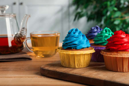 Delicious cupcakes with colorful cream on wooden tableの写真素材