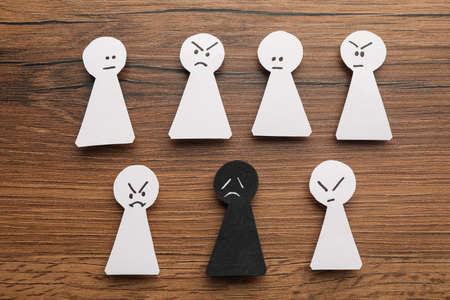 Flat lay composition with black and white paper figures on wooden table. Racism conceptの写真素材