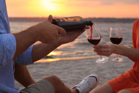 Lovely couple having picnic near river at sunset, closeup