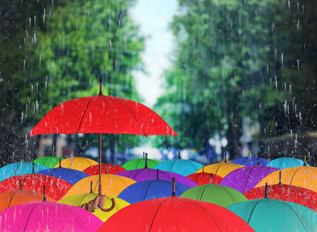 Person holding umbrella over other under heavy rain outdoorsの写真素材