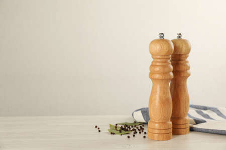 Wooden salt and pepper shakers with napkin on table against white background, space for text. Spice millの写真素材