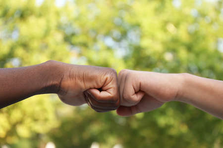 Men making fist bump outdoors, closeup viewの写真素材