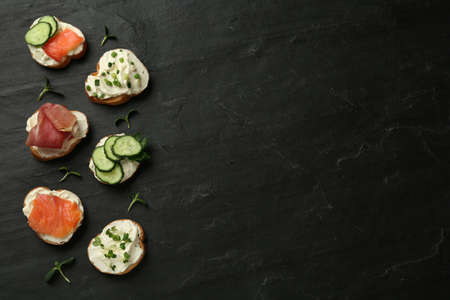 Delicious sandwiches with cream cheese and other ingredients on black table, flat lay. Space for textの写真素材