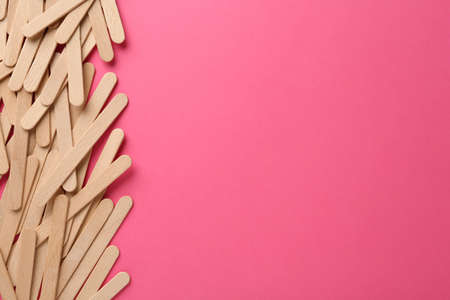 Wooden waxing spatulas on bright pink background, flat lay. Space for textの写真素材