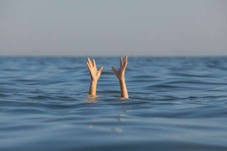 Drowning woman reaching for help in seaの写真素材