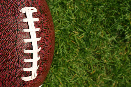 Top view of American football ball on green field grass, closeup. Space for textの写真素材