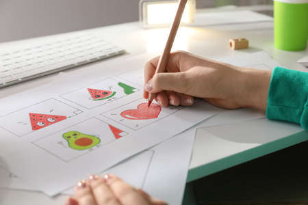 Woman drawing cartoon sketch at workplace, closeup. Pre-production process