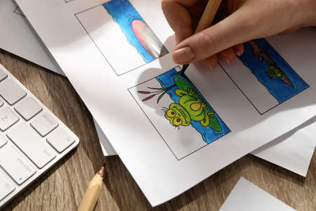 Woman drawing cartoon sketch in storyboard at workplace, closeup. Pre-production process