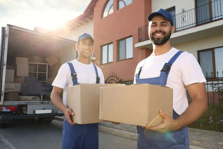 Workers unloading boxes from van outdoors. Moving serviceの写真素材