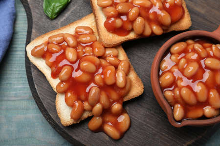 Toasts with delicious canned beans on light blue wooden table, top viewの写真素材