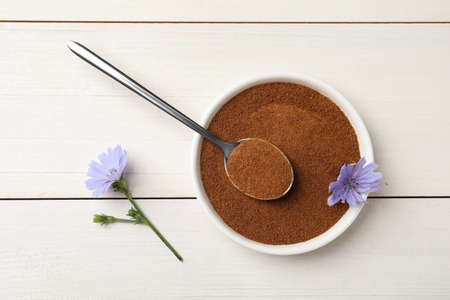 Bowl of chicory powder and flowers on white wooden table, flat layの写真素材