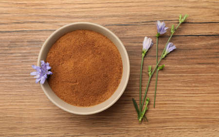 Bowl of chicory powder and flowers on wooden table, flat layの写真素材