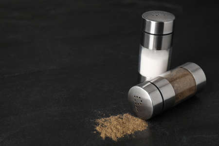 Salt and pepper shakers on black table. Space for textの写真素材
