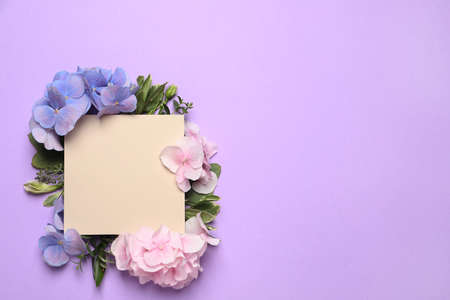 Beautiful hortensia flowers and blank card on violet background, flat lay. Space for text