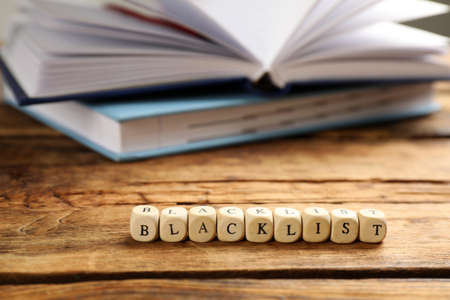 Cubes with word Blacklist and notebooks on wooden table, closeupの写真素材
