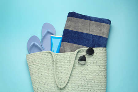 Beach bag with towel, flip flops, sunglasses and sun protection product on light blue background, top viewの写真素材