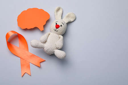 Orange ribbon, paper brain cutout and toy bunny on light gray background, flat lay with space for text. Multiple sclerosis awarenessの写真素材
