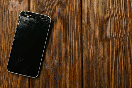 Damaged smartphone on wooden table, top view with space for text. Device repairingの写真素材