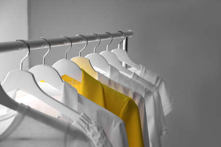 Yellow jacket hanging on rack among other clothes. Diversity conceptの写真素材