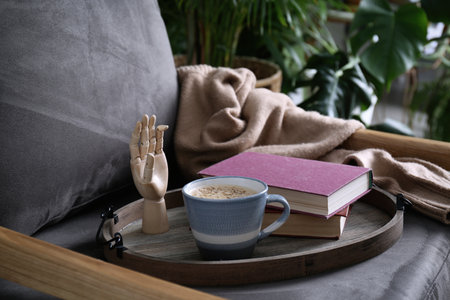 Wooden tray with books and coffee on armchair indoorsの写真素材