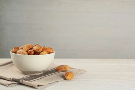 Ceramic bowl with almonds on white wooden table, space for text. Cooking utensilの写真素材