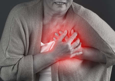 Mature woman having heart attack on dark backgroundの写真素材