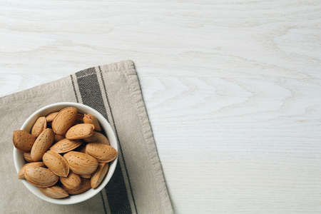 Ceramic bowl with almonds on white wooden table, top view and space for text. Cooking utensilの写真素材