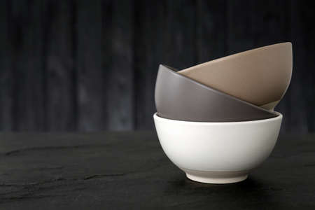 Stylish empty ceramic bowls on black table, space for text. Cooking utensilsの写真素材